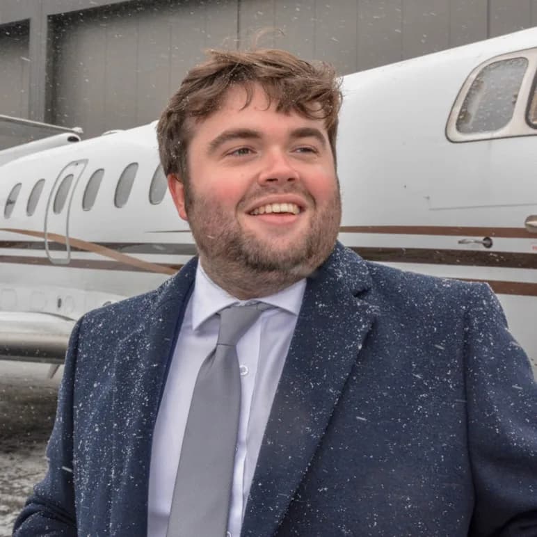 Person standing in front of a white aircraft in snowy conditions.