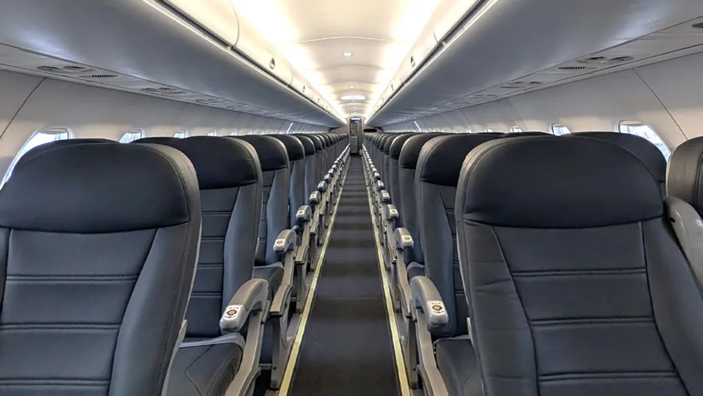 A view down the aisle of an aircraft cabin with rows of black leather seats.