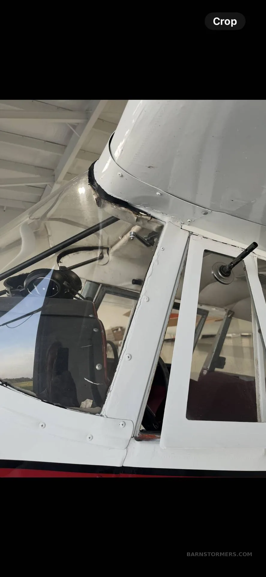 Close-up view of the cockpit windshield and side window of a white aircraft, showing the interior.