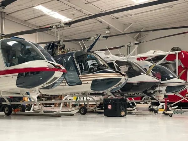 Several MD 500 helicopters are parked in a hangar.