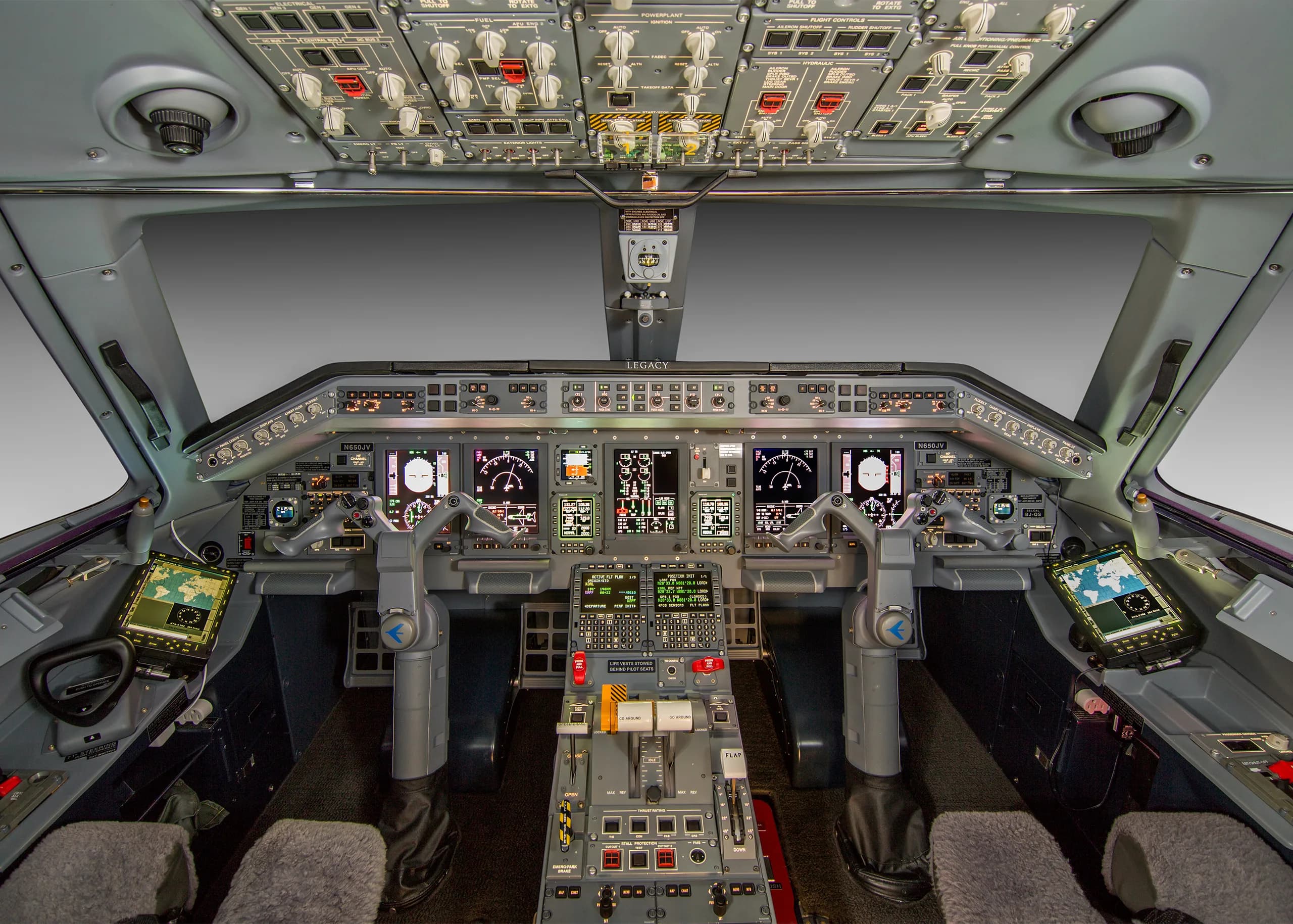 The detailed cockpit of an Embraer Legacy aircraft, featuring multiple display screens and numerous controls.