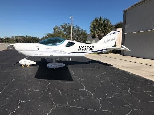 A white Sport Cruiser aircraft with tail number N137SC parked on the tarmac.