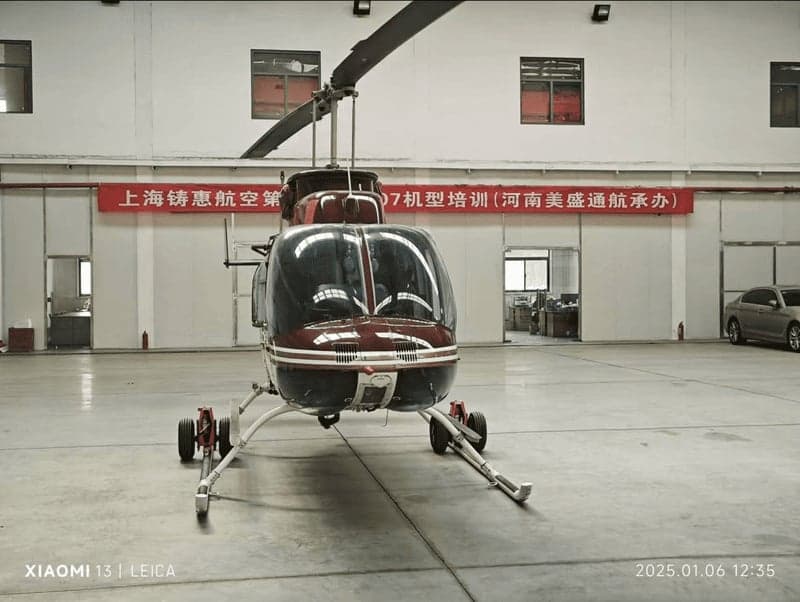 Front view of a red and white helicopter inside a hangar.