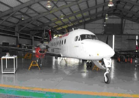 A white turboprop aircraft parked inside a hangar.