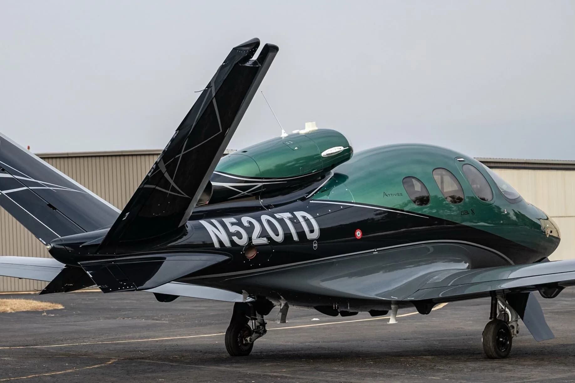 A three-quarter rear view of the Cirrus Vision Jet N520TD in green and black paint scheme.