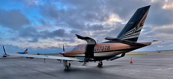 Pilatus PC-12 aircraft N970TB on the tarmac with the door open.