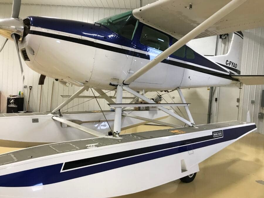 Close up of a white and blue Cessna on floats inside a hangar.