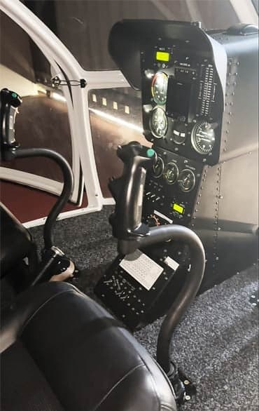 The cockpit of a helicopter with black seats and a black instrument panel.