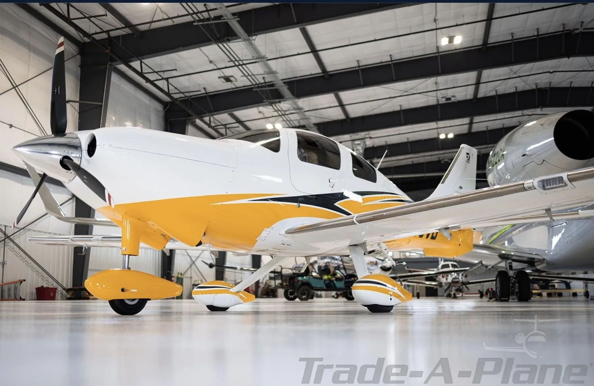 A white and yellow Cessna TTx aircraft with black accents is parked in a hangar.