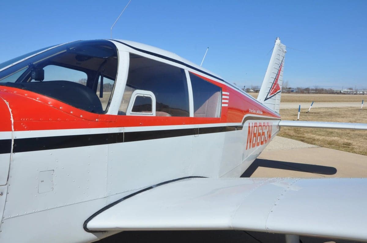 Side view of a Cherokee 180 aircraft showing the wing and tail.