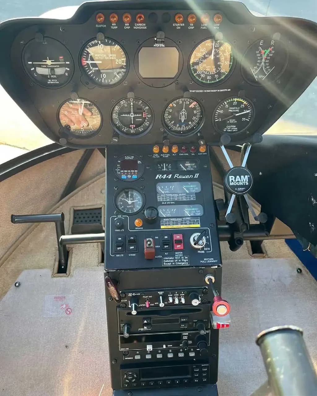 The instrument panel and center console of a Robinson R44 Raven II helicopter cockpit.