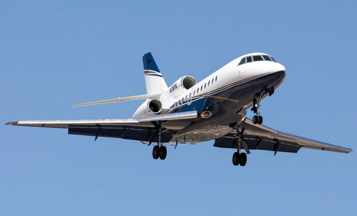 A Falcon aircraft with tail number N361K is seen in flight with landing gear down.