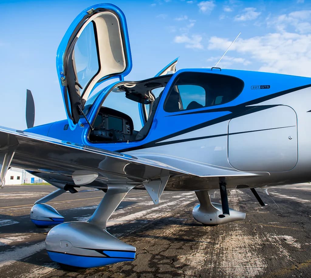 A close-up view of the open doors and landing gear of the blue and silver Cirrus SR22T GTS Carbon aircraft (N127DF).