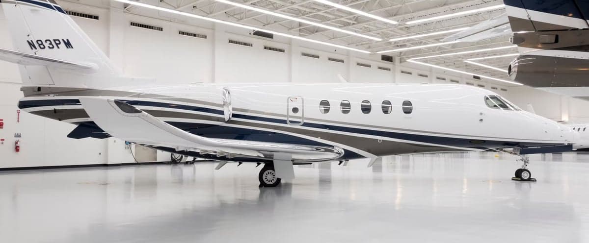 Side view of a white and gray Cessna Citation Latitude in a hangar.