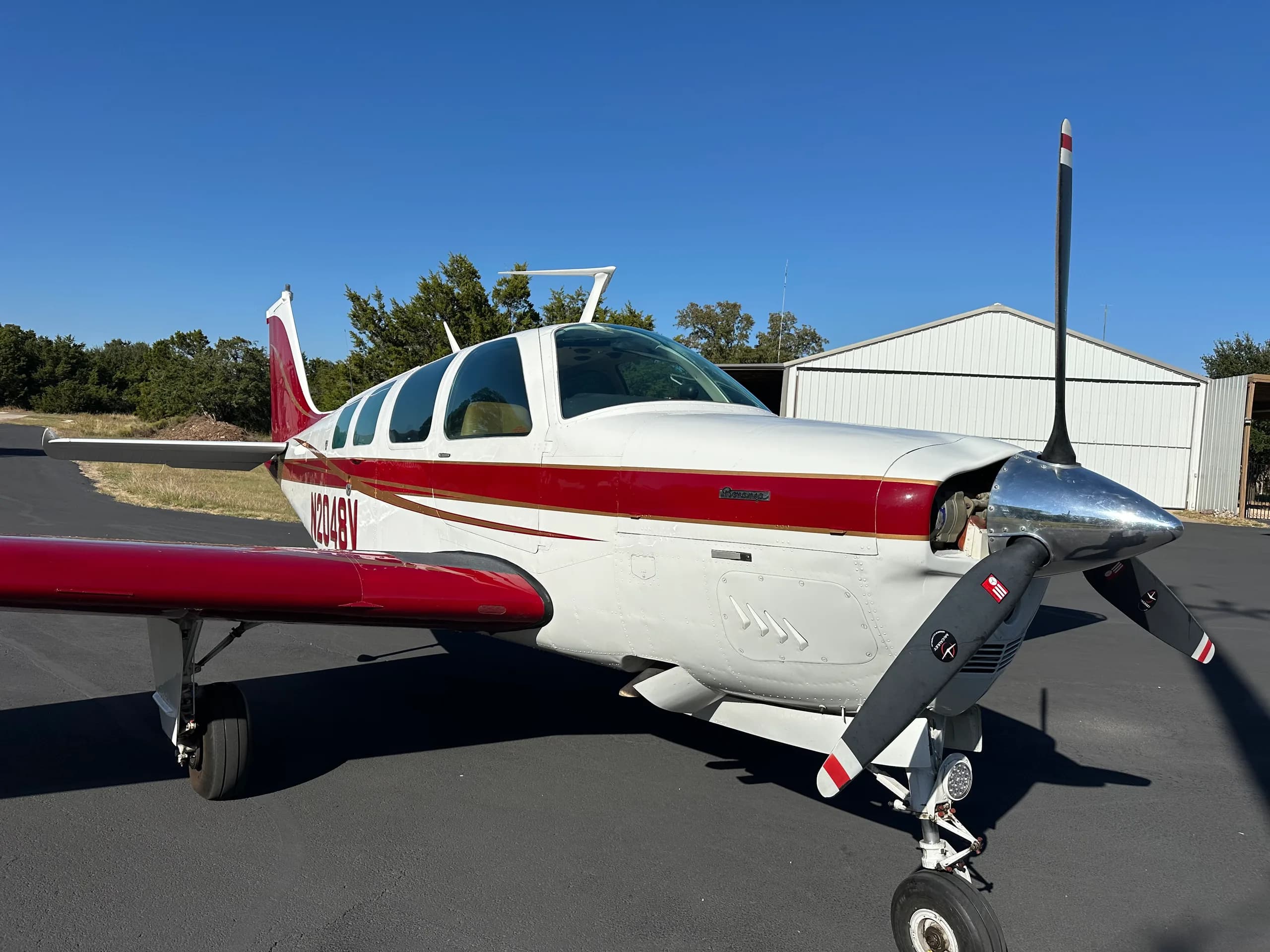 A close-up of the front of a Beechcraft Bonanza aircraft with a white and red paint scheme.