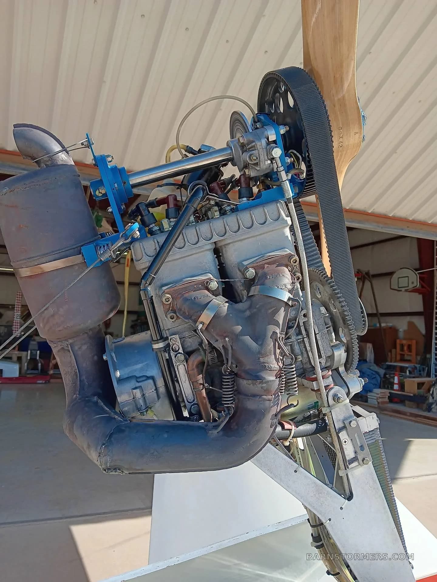 A detailed close-up of the Grob G 103 glider's retractable engine, highlighting the exhaust system and belt drive.