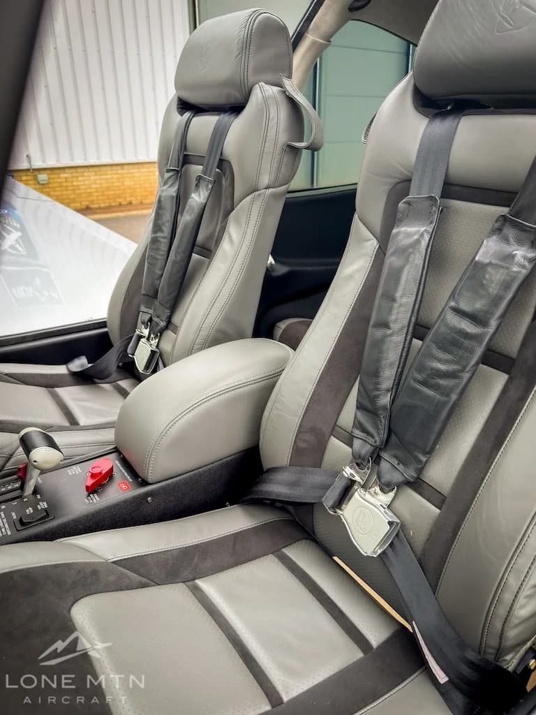 The gray and dark gray front seats of an aircraft cabin with seatbelts and a center console.