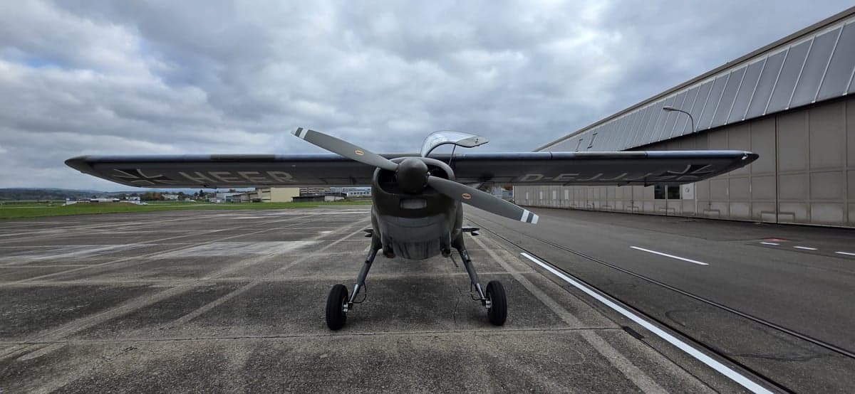 Front view of a gray and green aircraft on the tarmac.