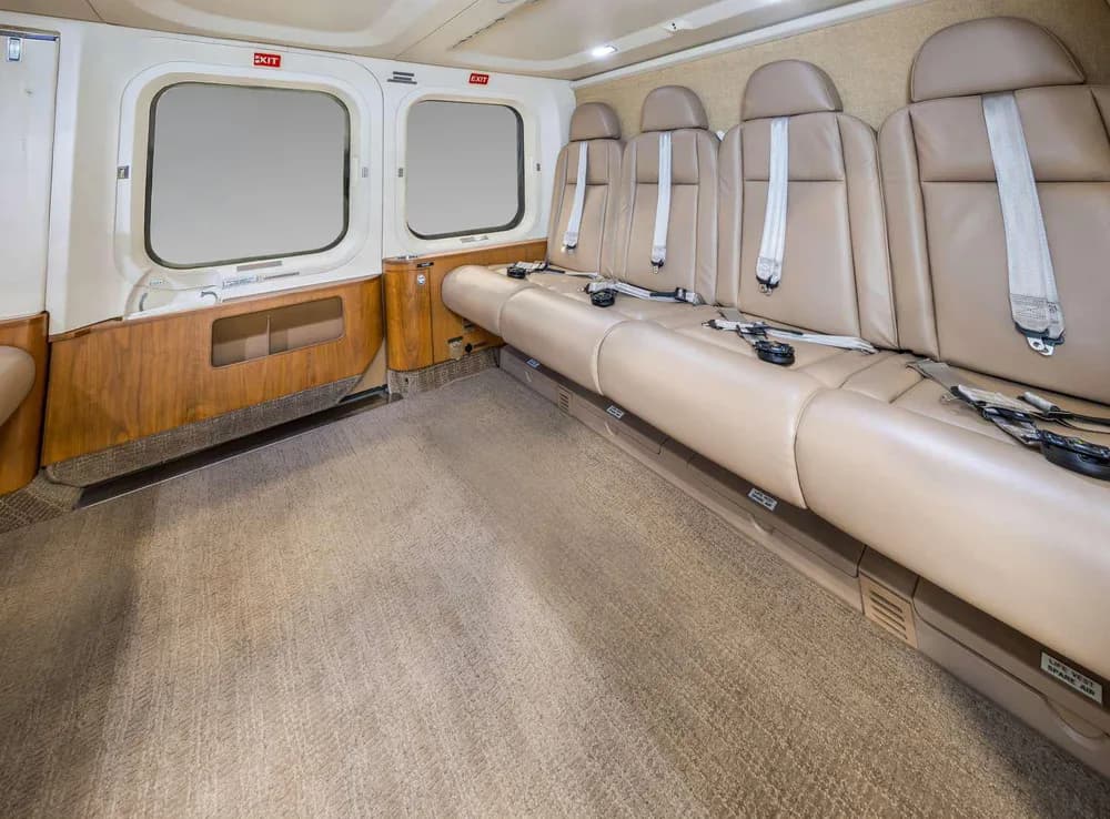 A wider view of the helicopter's interior cabin with tan leather seats and a beige carpet.