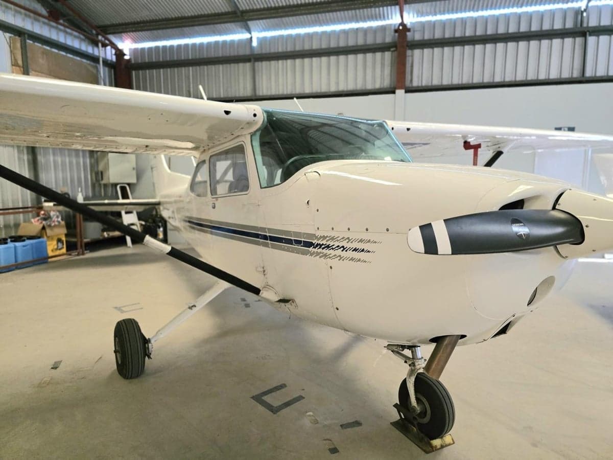 A Cessna aircraft is parked inside a hangar, showing the front and propeller.