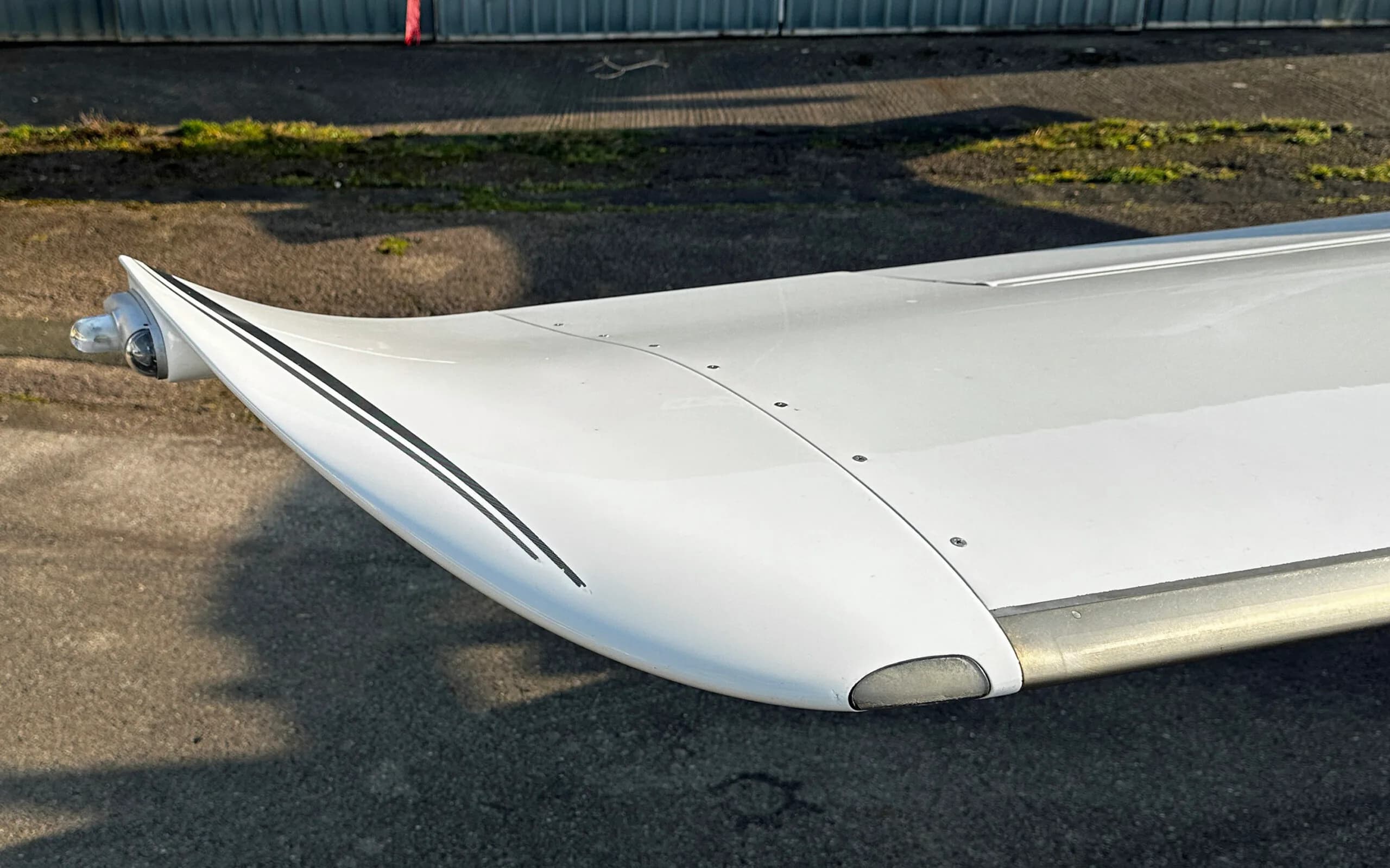 Close-up view of the white wingtip of a Cirrus SR22 Turbo aircraft with black stripes.