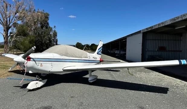 Side view of a white and blue aircraft with a cover on the cockpit.