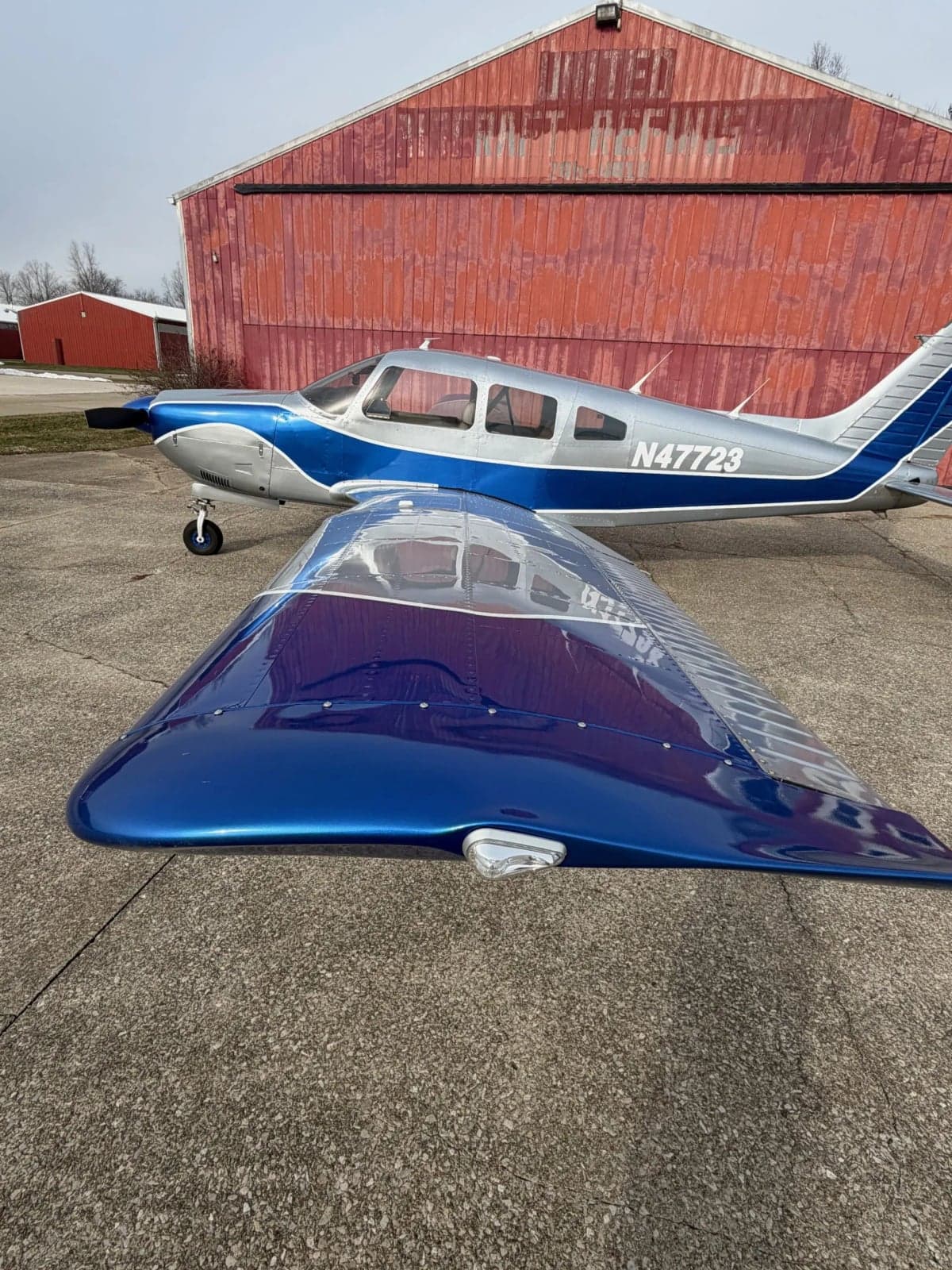A Piper PA-28-181 Archer II aircraft with registration N47723 parked on the tarmac in front of a hangar.