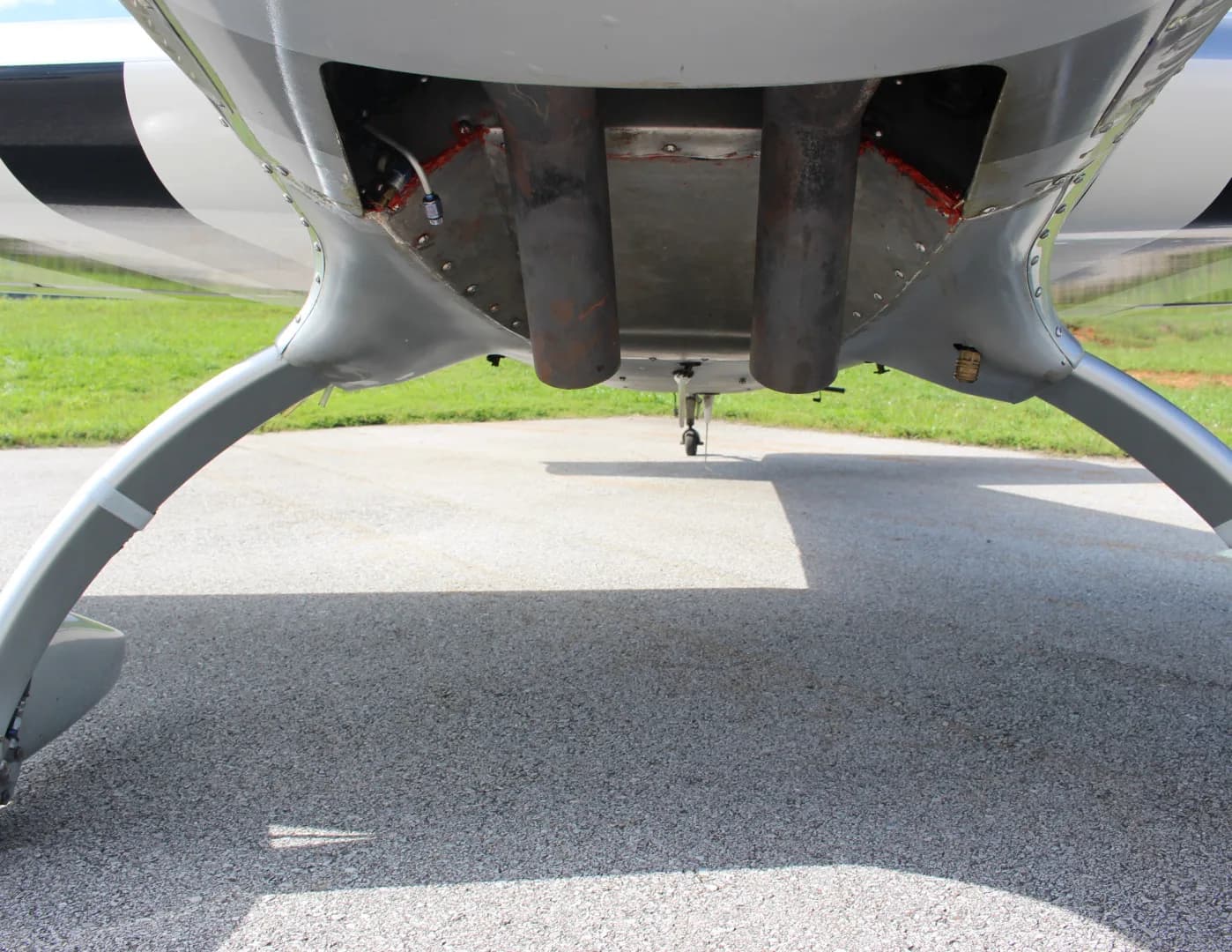 An underside view of the N51E Extra EA-300/L aircraft, showing its landing gear and exhaust pipes.