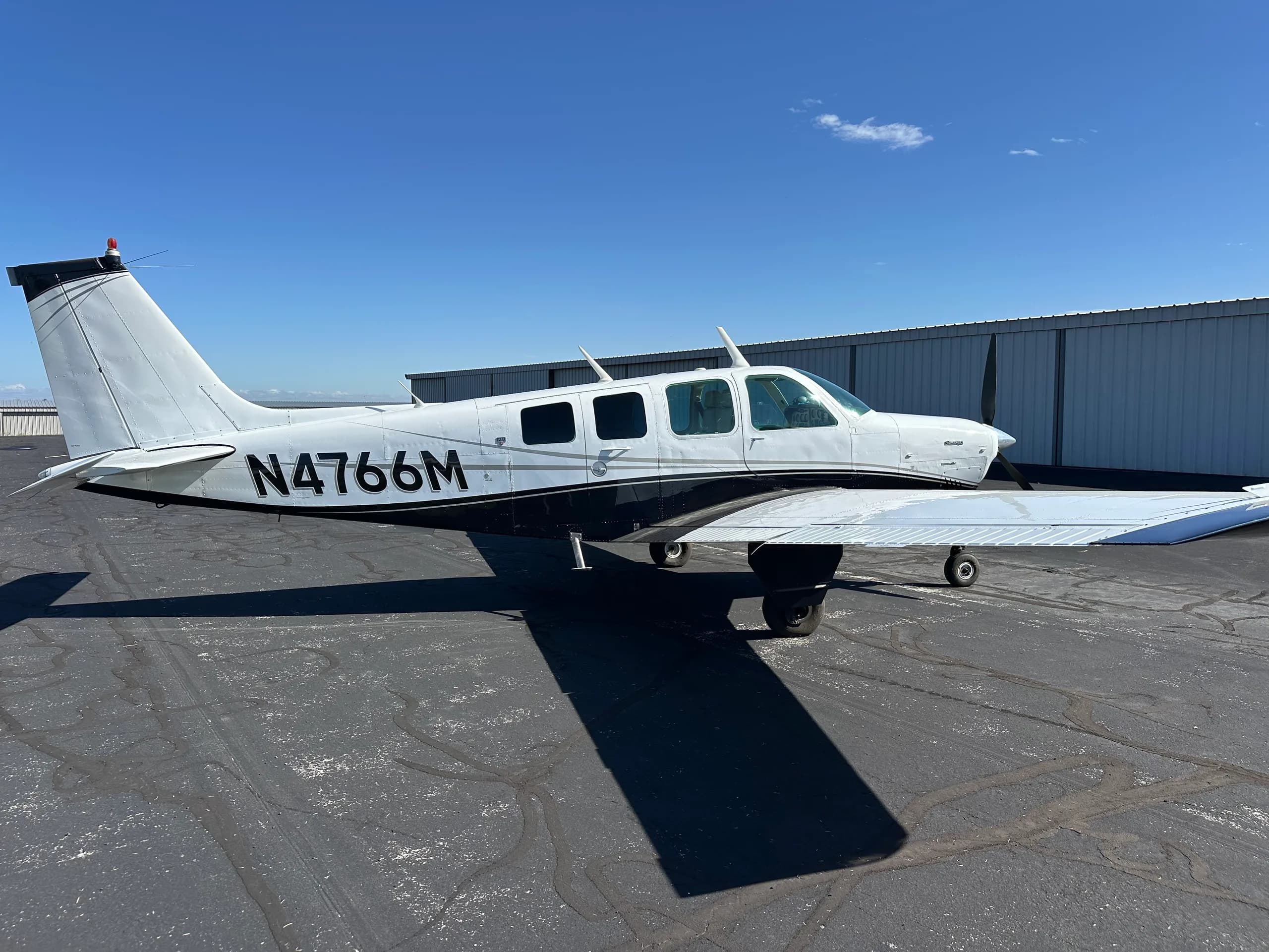 A Beechcraft Bonanza aircraft with registration N4766M is parked on the tarmac.