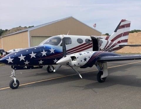 A Beechcraft King Air with a custom American flag paint scheme on the ramp.