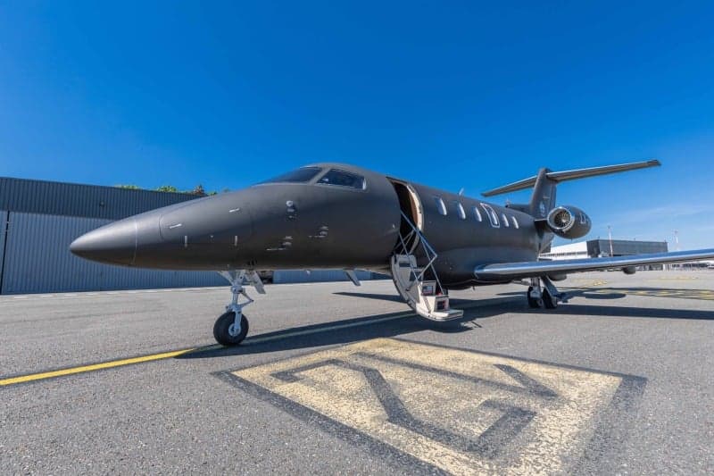 A Bombardier Challenger 350 aircraft with registration LX-VGF is parked on the tarmac at an airport with the stairs down.