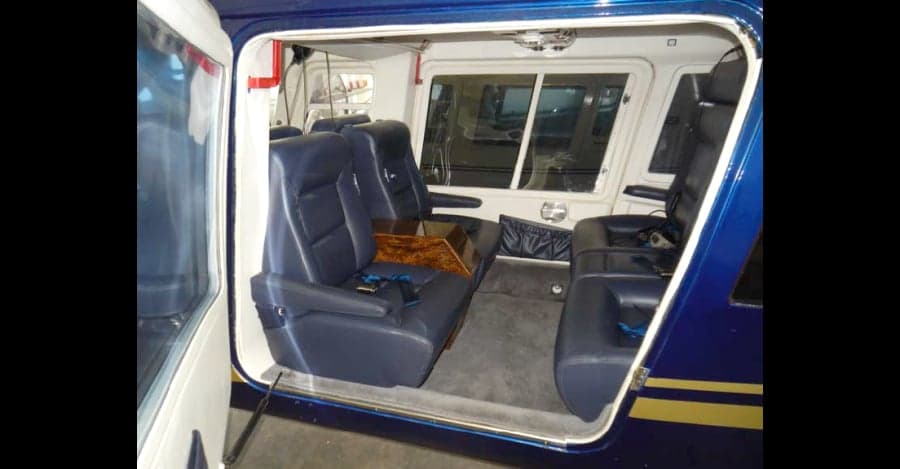 The helicopter's interior features blue leather seats and a wood-trimmed center console.