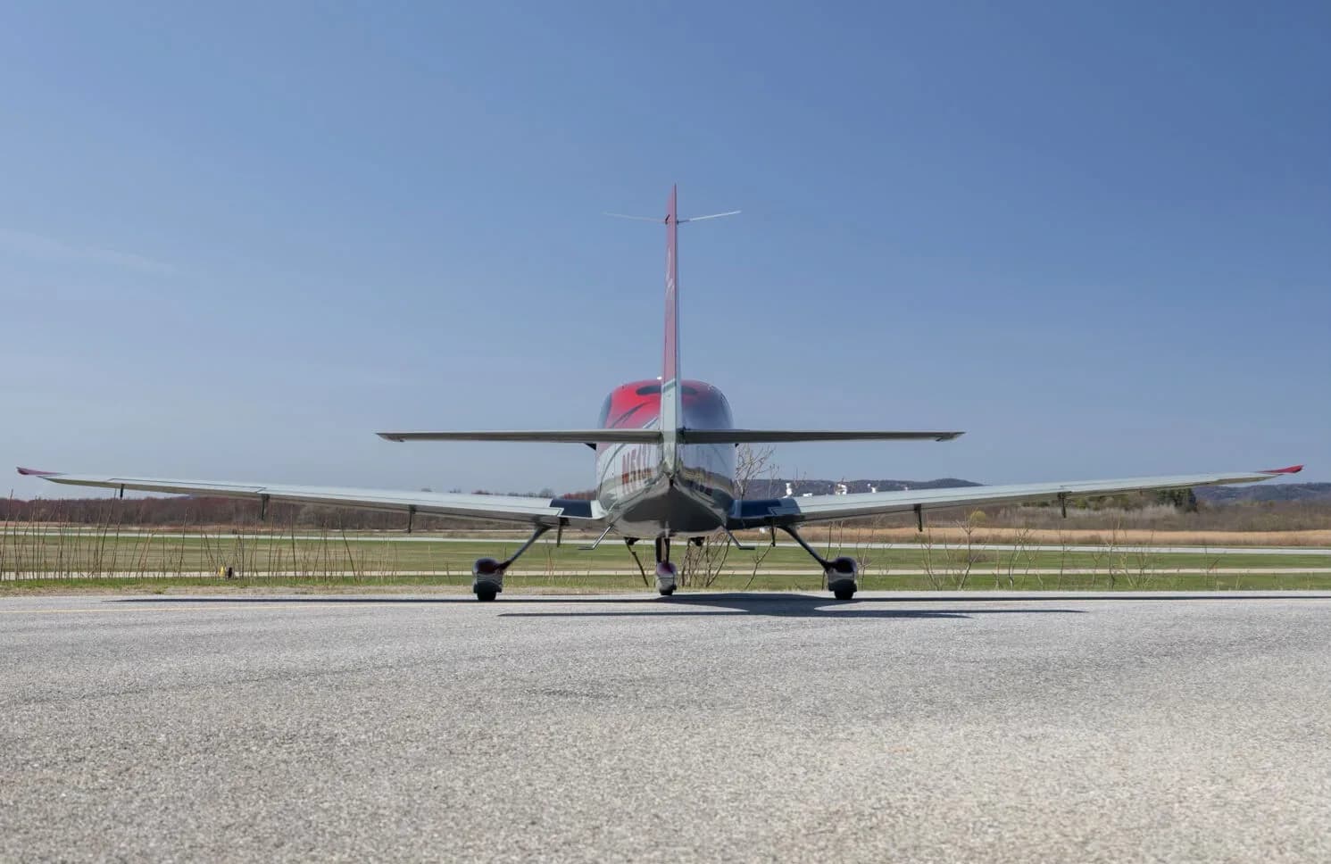 Rear view of the red and grey Cirrus SR22T aircraft (N513Z) on an asphalt runway.