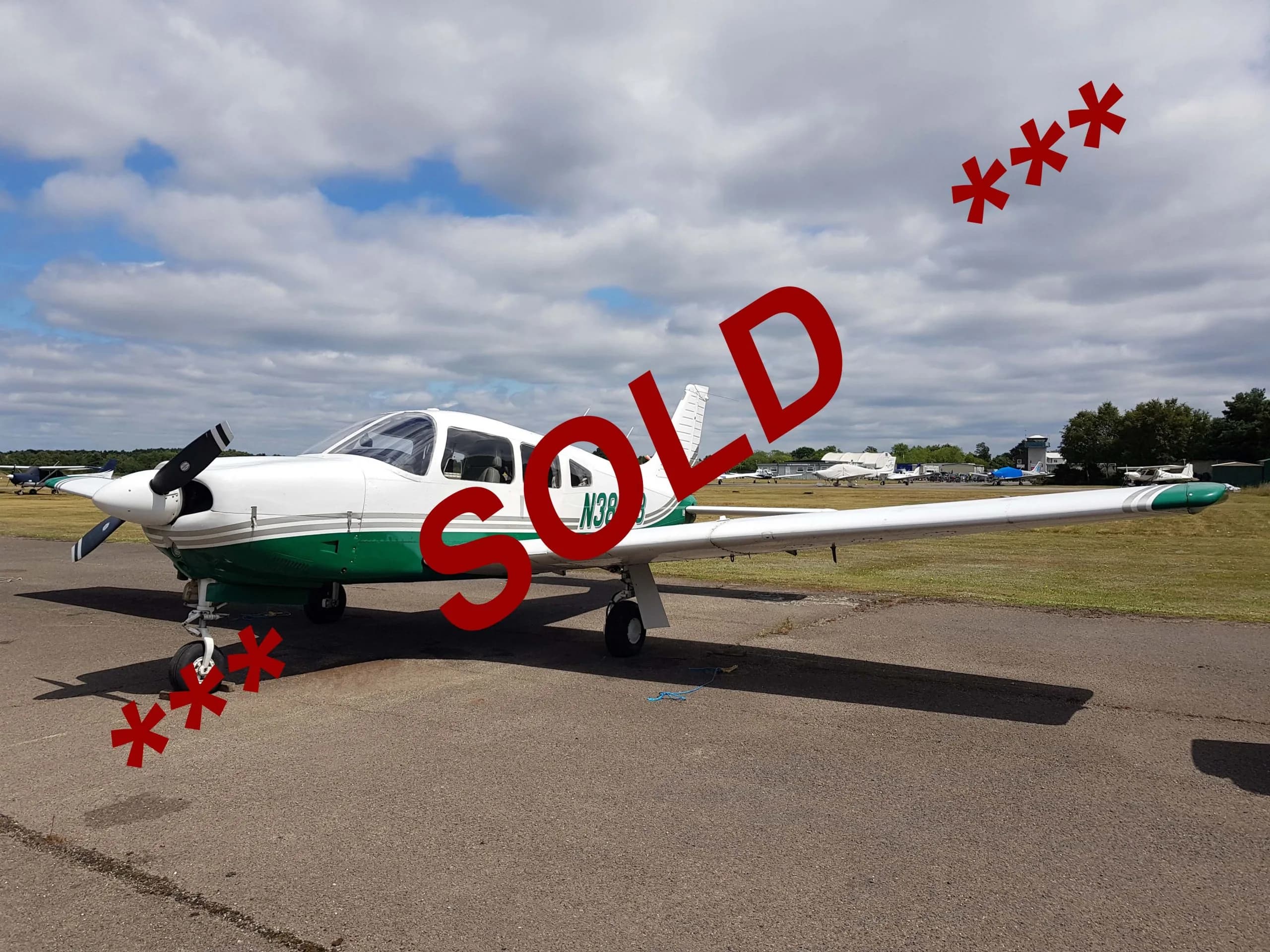 A white and green single-engine propeller aircraft with registration N38xx is parked on an airfield under a cloudy sky, with 'SOLD' overlaid.