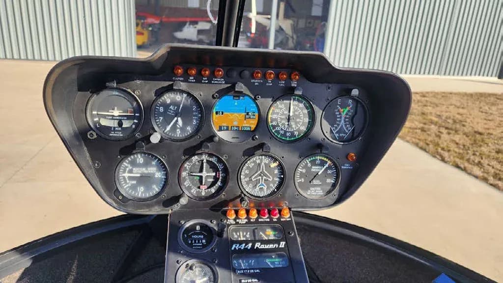 The instrument panel of a Robinson R44 Raven II helicopter displays various gauges and controls.
