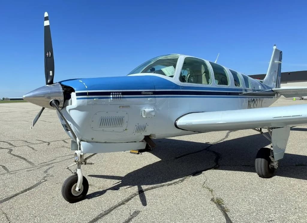 Front quarter view of a white and blue Beechcraft Bonanza N39TK on the tarmac.