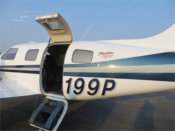 Side view of the Malibu Mirage aircraft with the door open, showing the tail number.