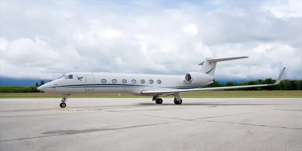 Gulfstream G650ER aircraft on the tarmac with a cloudy sky overhead.