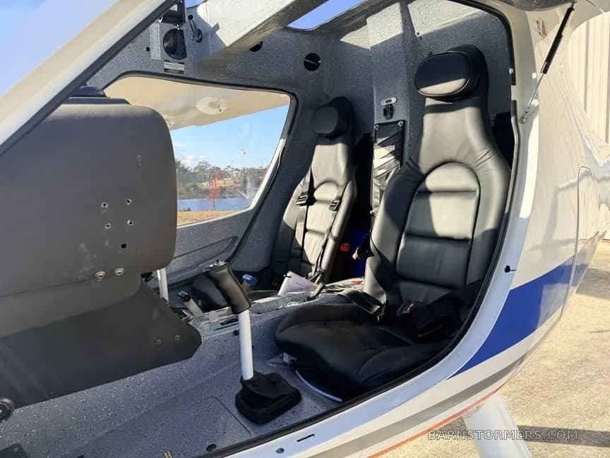 The two-seat black leather interior of a light sport aircraft, showing the cockpit entry and controls.