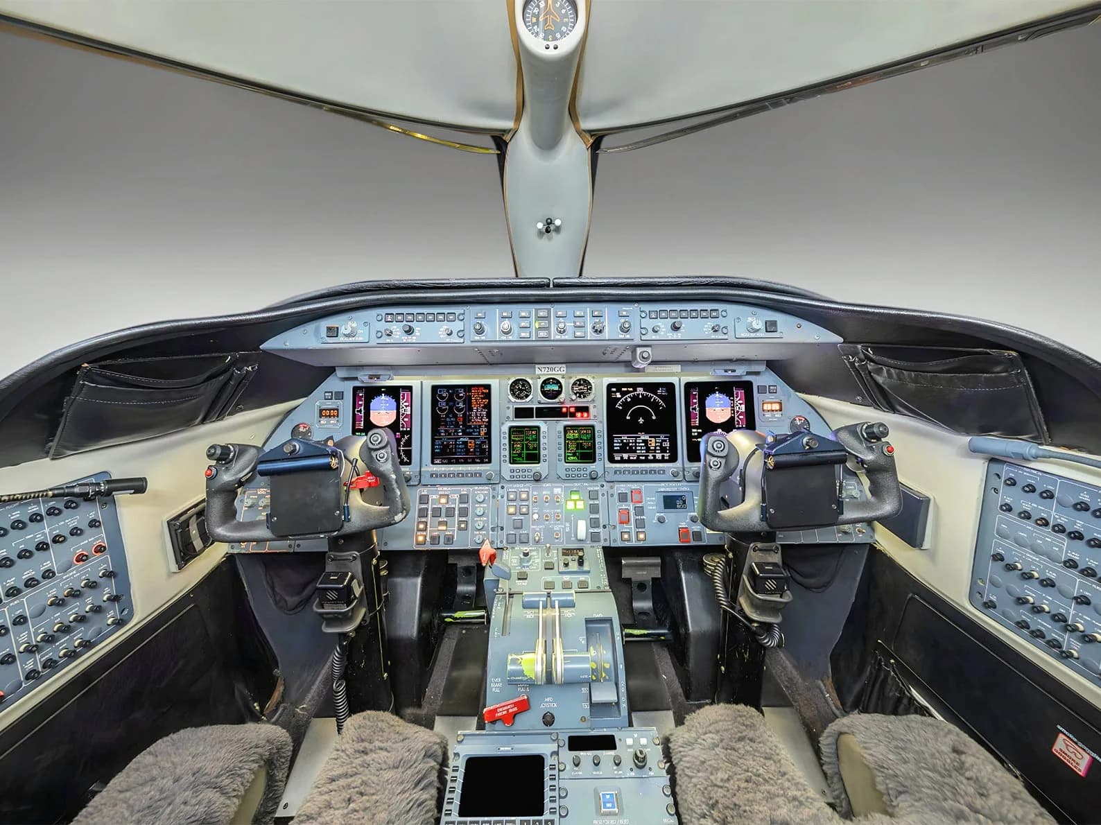 The cockpit of a business jet with multiple display screens, yokes, and control panels.