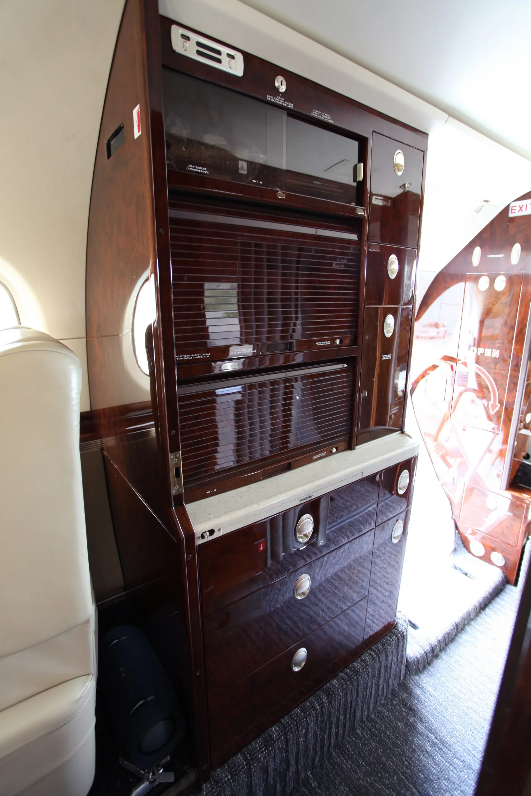 The interior of a Hawker 400XP aircraft with wooden cabinets and storage.