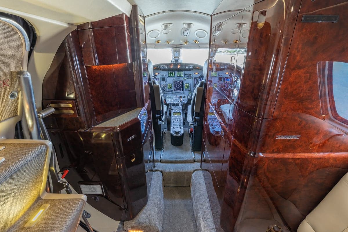 View of the aircraft cabin with wood paneling and a cockpit view.