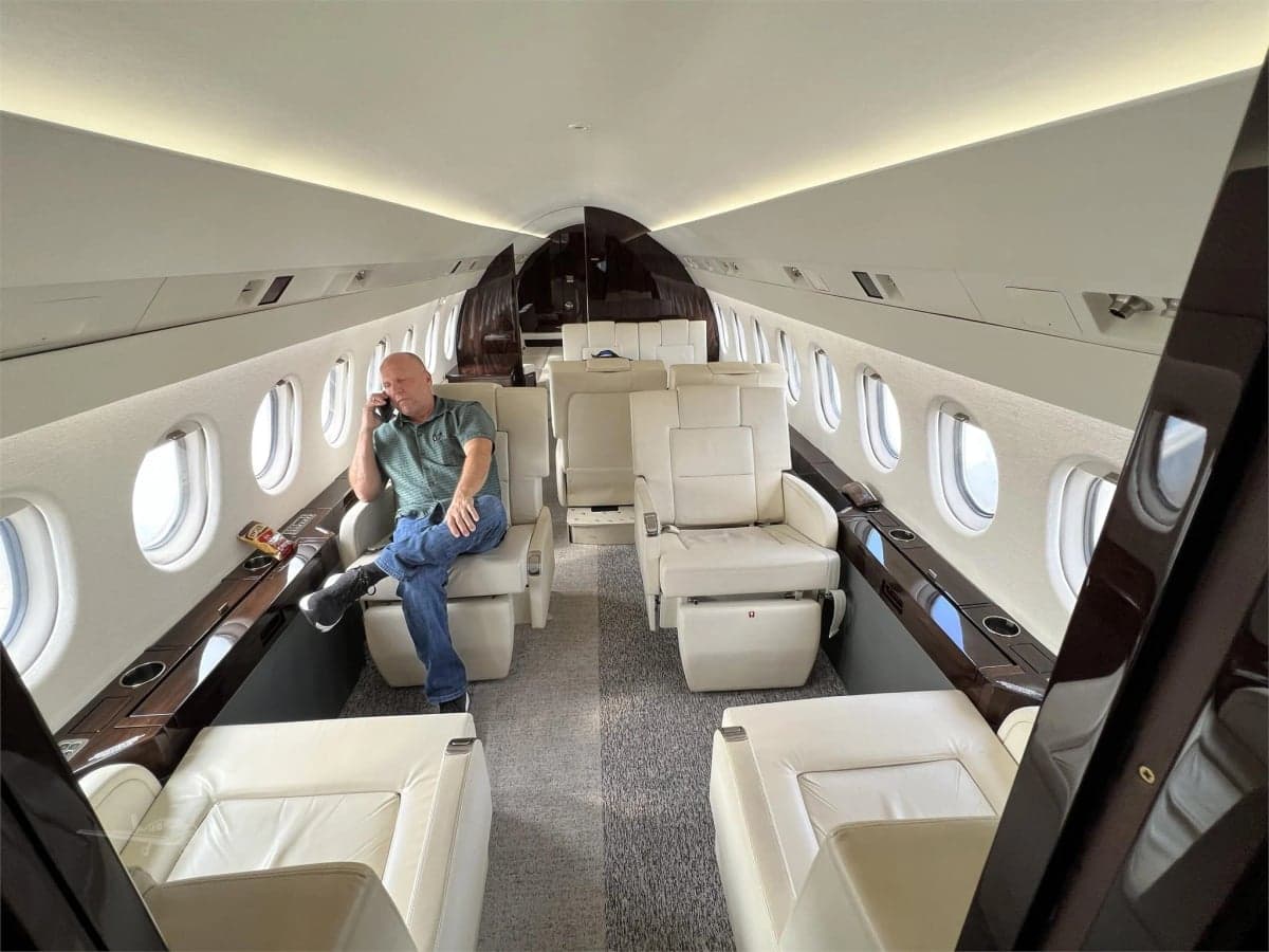 A white Falcon jet, registration N100UP, parked inside a hangar.