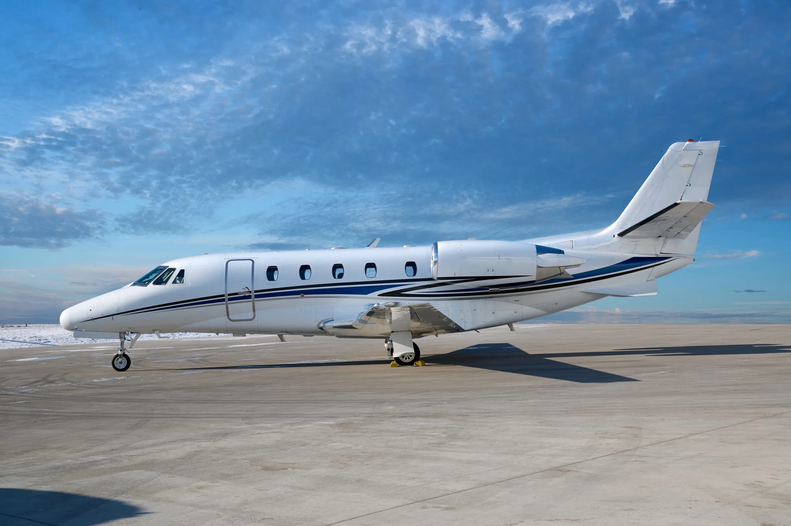 Side view of a white and blue Cessna Citation CJ3 on the tarmac.