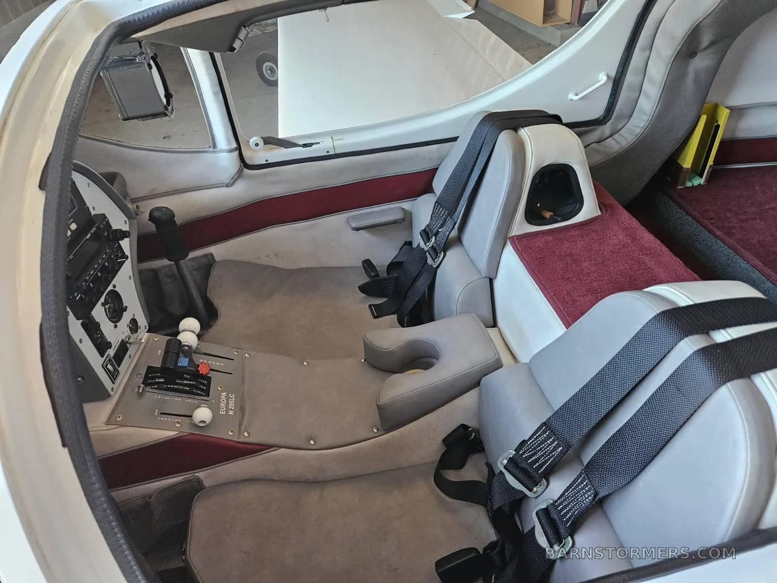 The interior cabin of a Europa aircraft showing grey seats, red carpet, and flight controls.