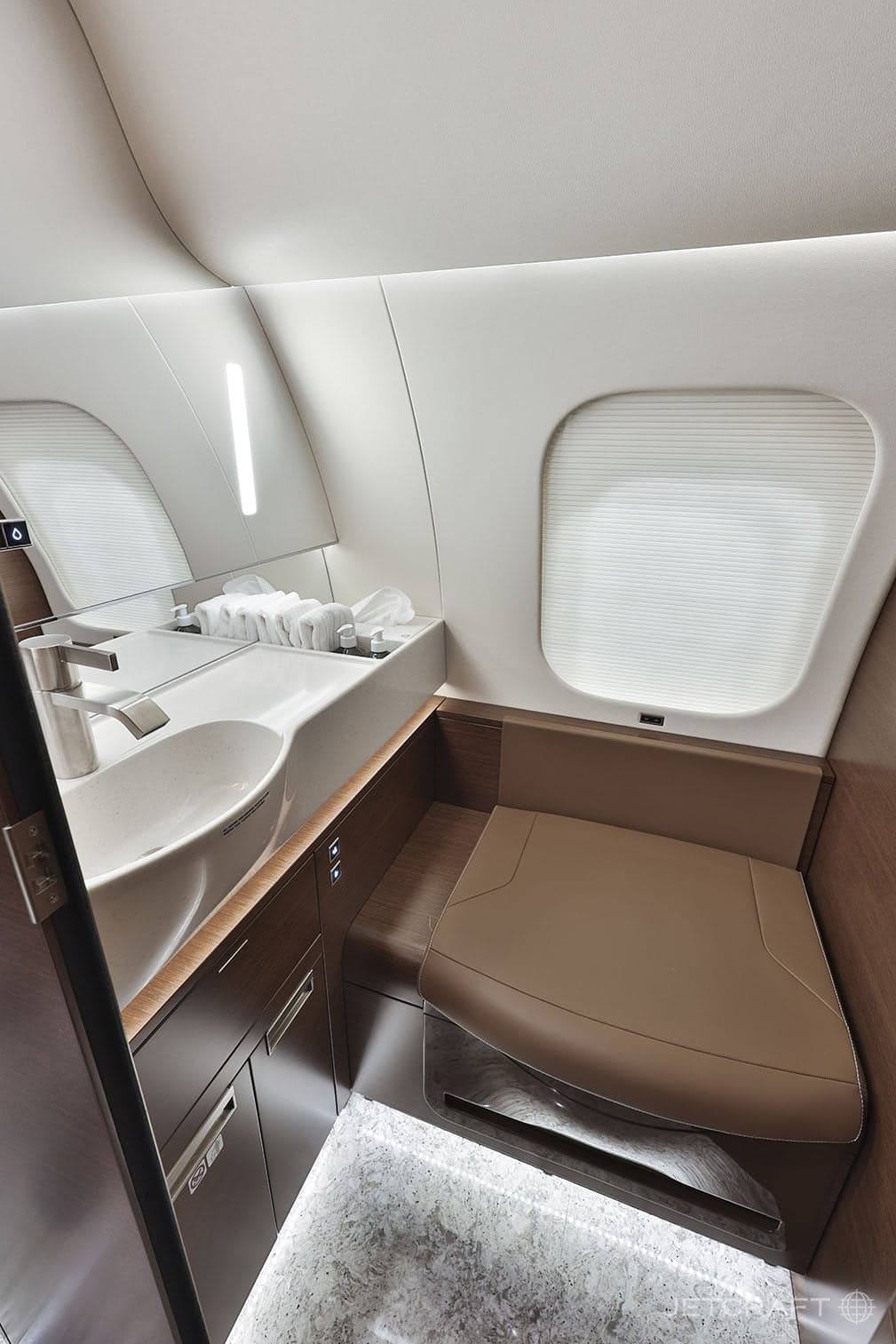 A lavatory with a sink and toilet in an aircraft.