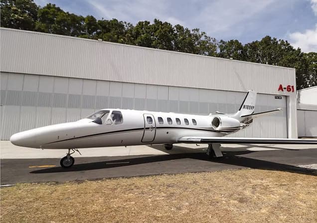 Citation CJ3 aircraft with the door open in front of a hangar.
