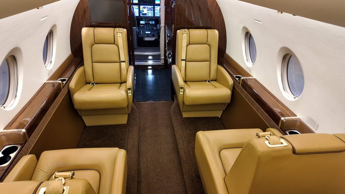 Interior view of the aircraft cabin with tan leather seats and a table.