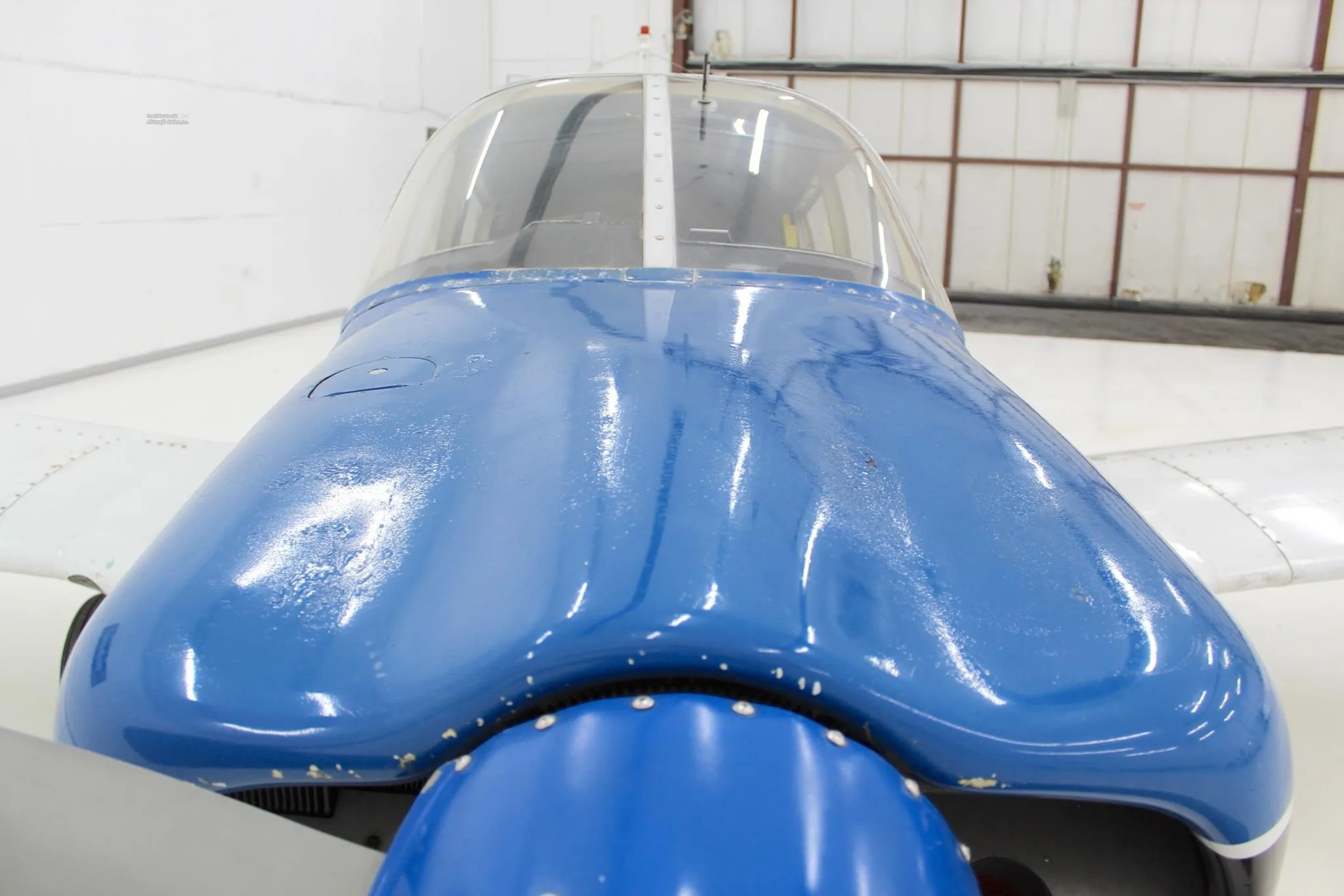 Close-up front view of the blue cowling and windshield of a single-engine aircraft.