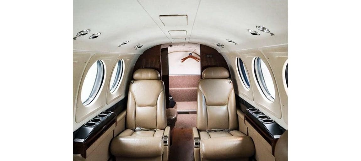 Aircraft interior with leather seats and window views.